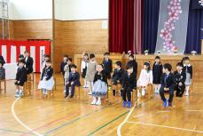 新入生紹介で名前を呼ばれ、元気よく返事をし立ち上がる新1年生(ステージ左側)