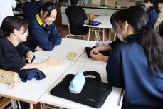 かわい氏がデザインした「Yorocaトラベルカード」を見る生徒